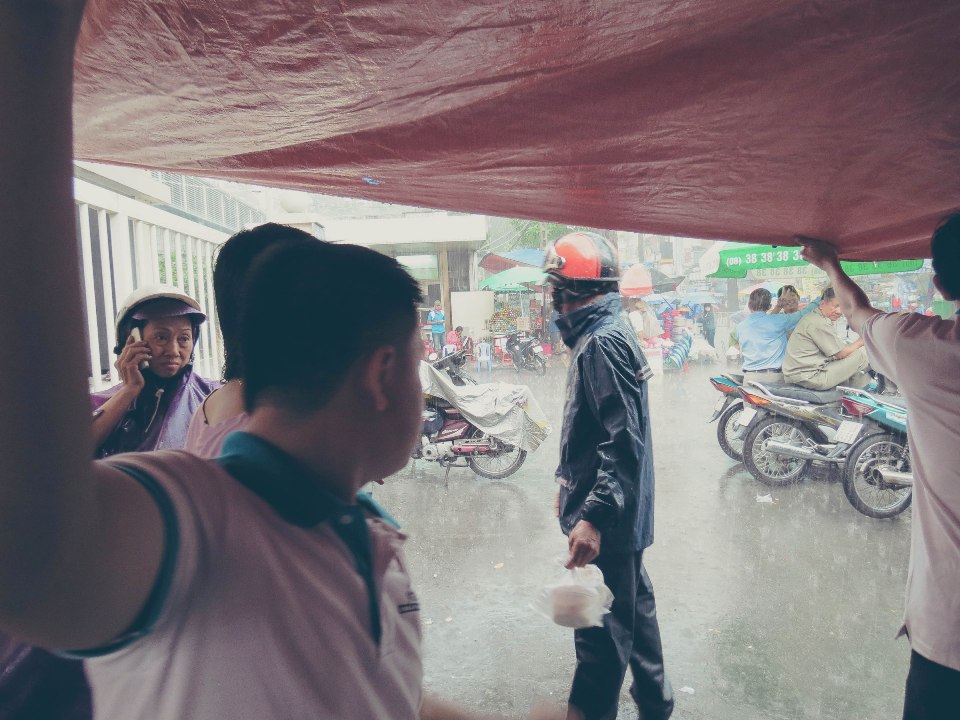Mặc gió mưa, mọi người vẫn mang áo mưa ra nhận những hộp cháo yêu thương từ VTAX
